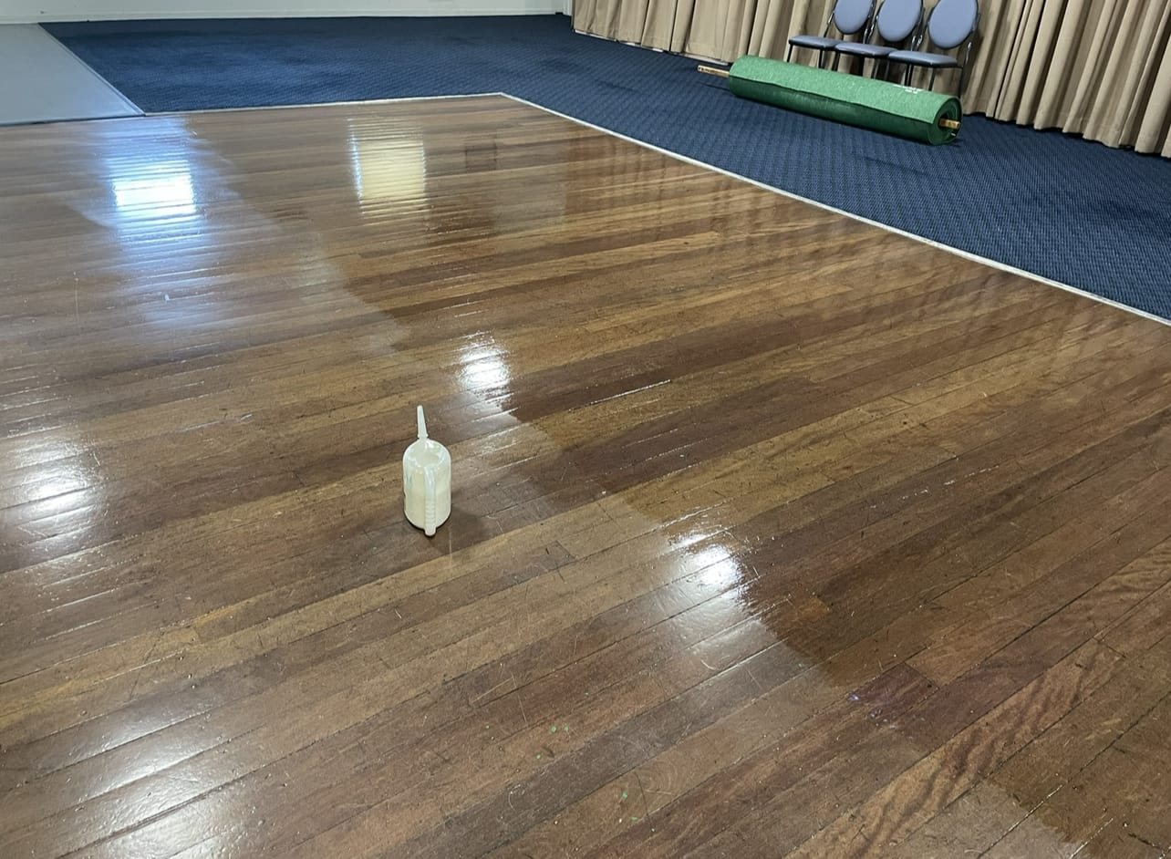 Fresh sealant being applied to a timber floor in a community hall